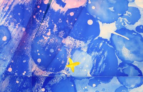 Detailaufnahme eines farbenfrohen Glaskunstwerks mit blauen und rosafarbenen Nuancen sowie einem kleinen, gelben Stern.