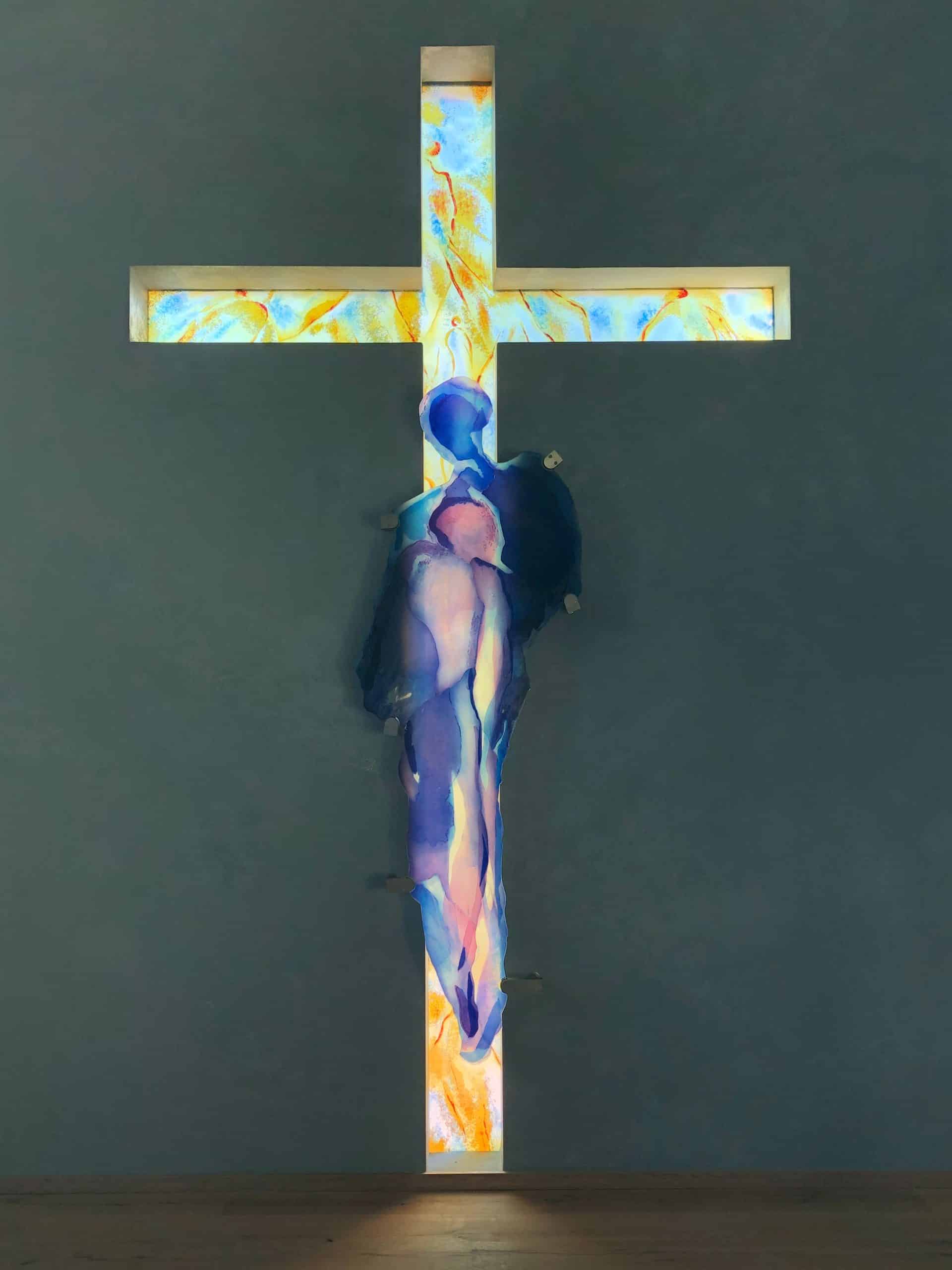 Farbenfrohes Glas-Kreuz mit abstrakter Darstellung von Jesus an der Wand. Warme Töne mit blau-violetten Akzenten.