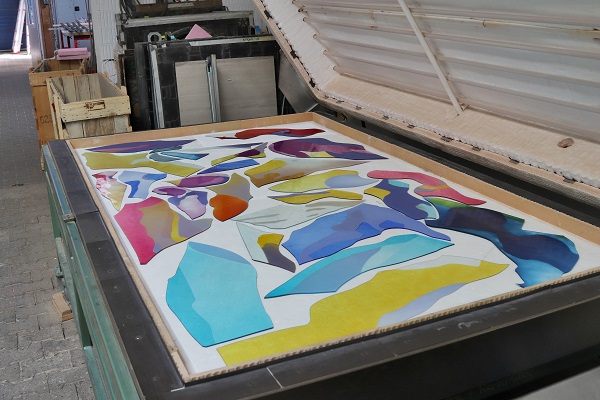 Farbenfrohes, abstrakte Glasscheiben mit lebhaften Formen auf einem Arbeitstisch in einem Atelier.