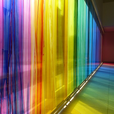 Colorful glass windows with vertical stripes in rainbow colors that are reflected on the bottom of a gang.