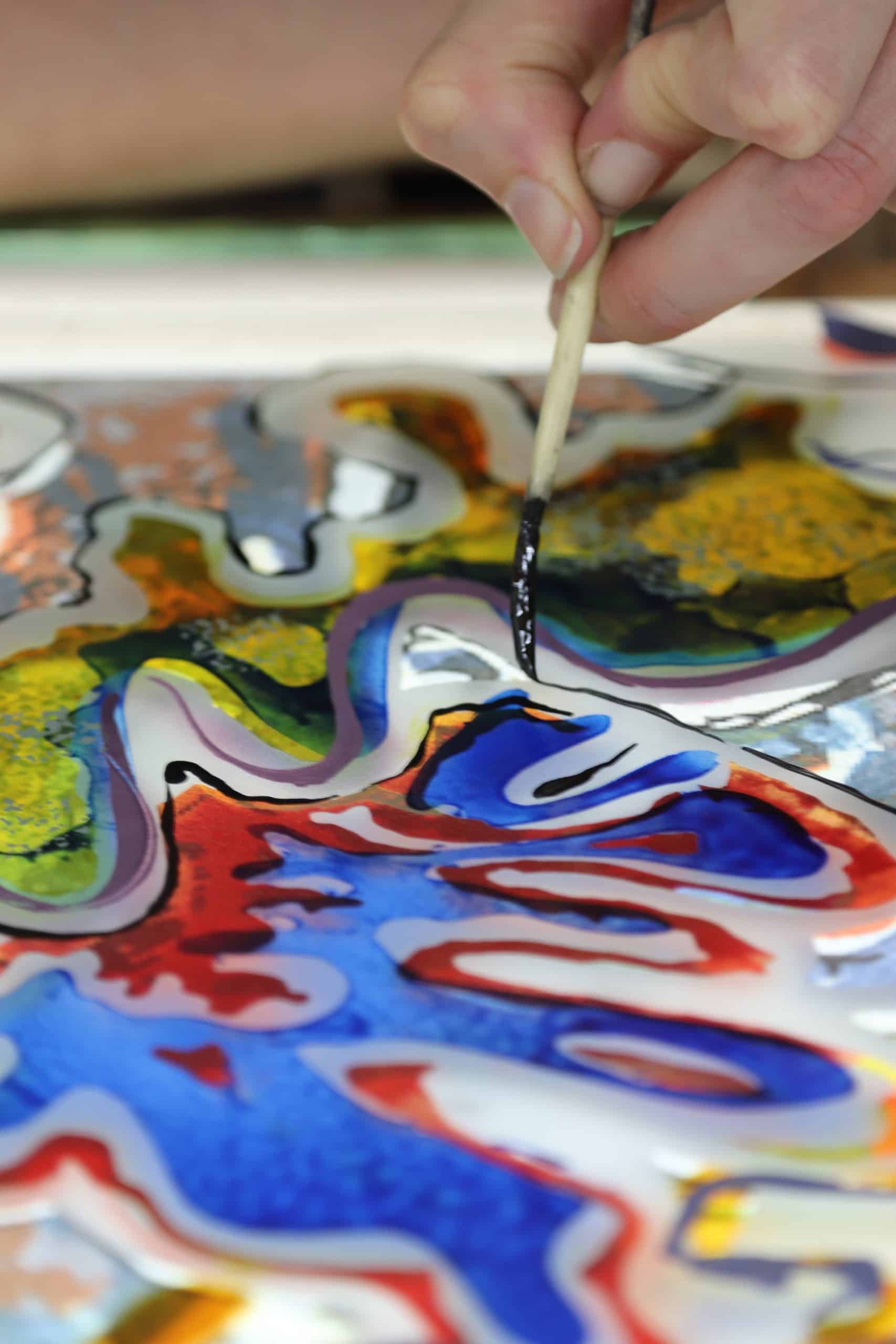 Hand bemalt mit Pinsel farbenfrohes, abstraktes Glaskunstwerk in Nahaufnahme.