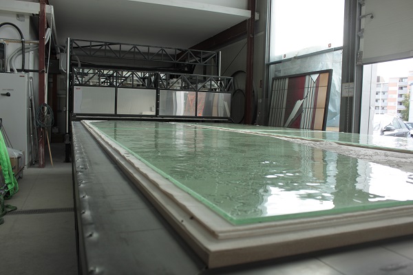 Large glass panel on a work table in a production hall, intended for artistic processing. Image visualizes our glass distillery.