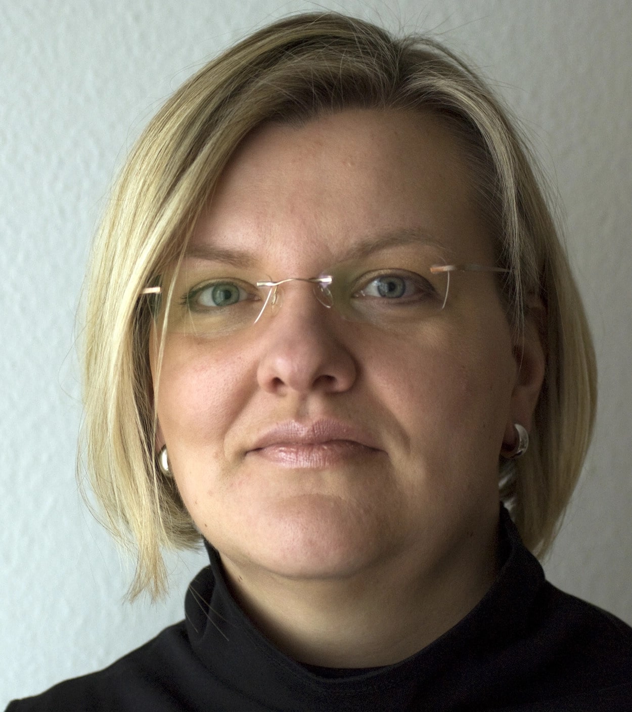 Porträt einer Frau (Frau Krämer-Marloh) mit blonden Haaren, Brillenträgerin, vor einem hellen Hintergrund.