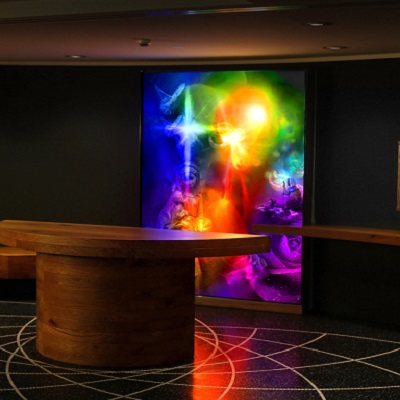 Colorful glass windows with abstract motifs in a dark room with wooden table and patterned soil.