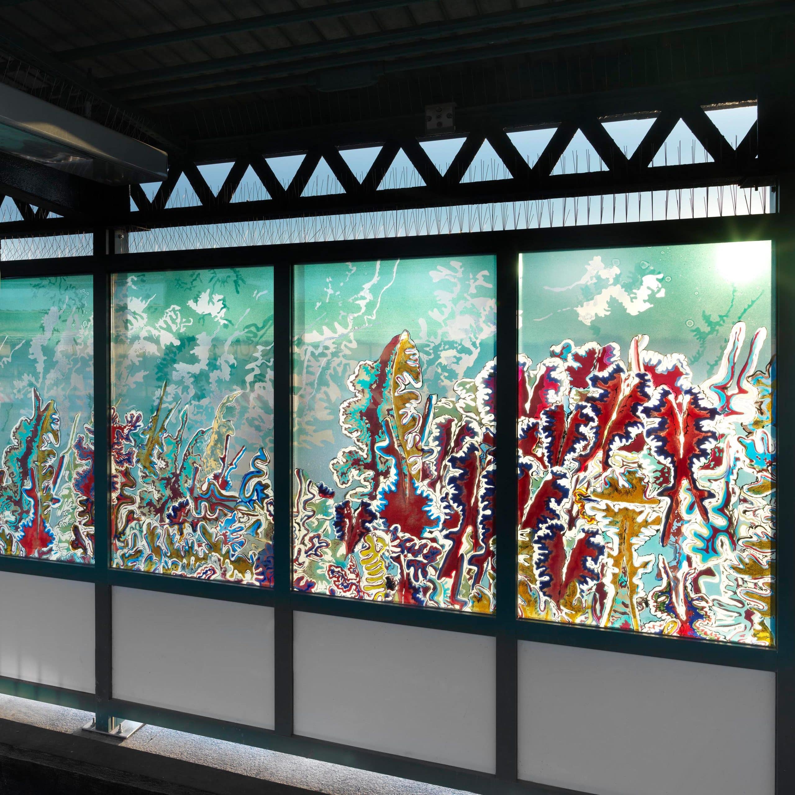 Colorful artistic glass panel windows in a train station with abstract patterns depicting coral reefs.