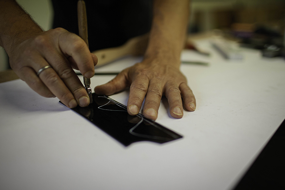 IMG_4348 copy Nahaufnahme der Hände eines Handwerkers beim präzisen Zuschnitt eines Glasstücks für ein Kunstwerk.