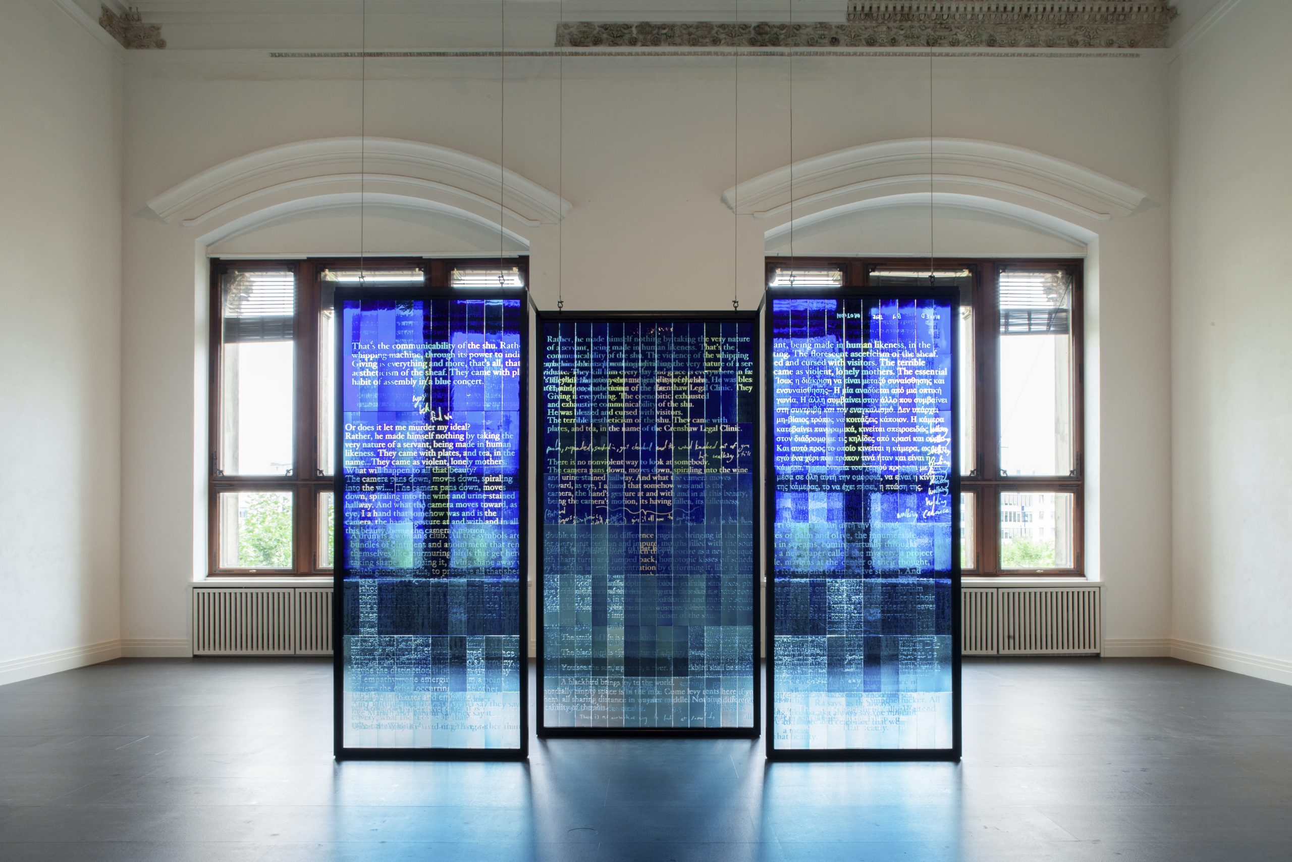 Moderner Glaskunst-Installationsblick in einem Raum mit hohen Decken, Text und Beleuchtung.